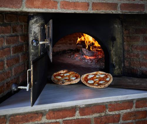 two pizzas are cooking in a brick oven at Yazz Collective in Fethiye