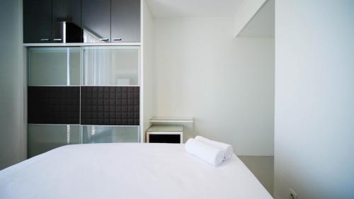 Cama blanca en habitación con cocina en Spacious and Homey 2BR at The Via and The Vue Apartment By Travelio, en Surabaya