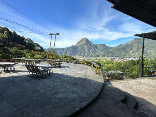 a patio with tables and chairs and a mountain at Bayview Beach Resort East Lombok in Labuan Lombok