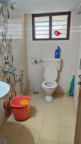a bathroom with a toilet and a sink and a bucket at Christa Homestay in Mangalore