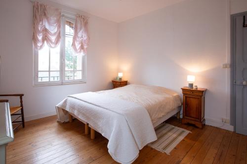 a white bedroom with a bed and two lamps at La Prévalaye - Proche du château de Pouancé in Armaillé