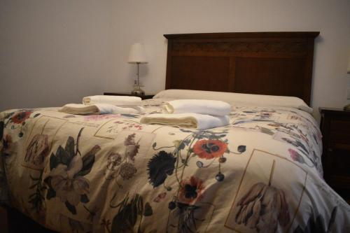 a bed with a flowered blanket with towels on it at Apartamentos Bodeguetas in Constantina