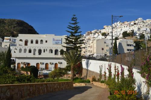 a street in front of a white building with a tree at Hotel Sim&oacute;n in Moj&aacute;car