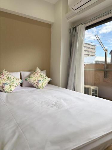 a white bed with two pillows and a window at Nishi-Ike Apartment Room 3 in Tokyo