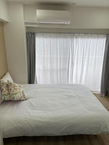 a bedroom with a white bed with a window at Nishi-Ike Apartment Room 3 in Tokyo