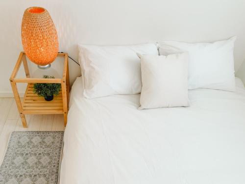 a bed with white pillows and a table with a lamp at Mirinae in Seoul