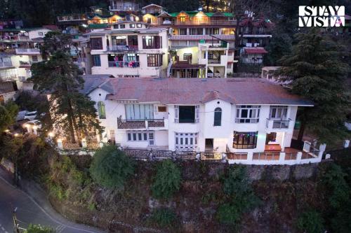 a large white house on top of a hill at StayVista at The Northern Lake House with Balcony in Nainital