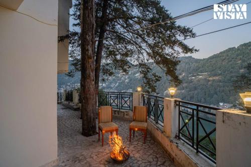 a patio with two chairs and a fire pit at StayVista at The Northern Lake House with Balcony in Nainital