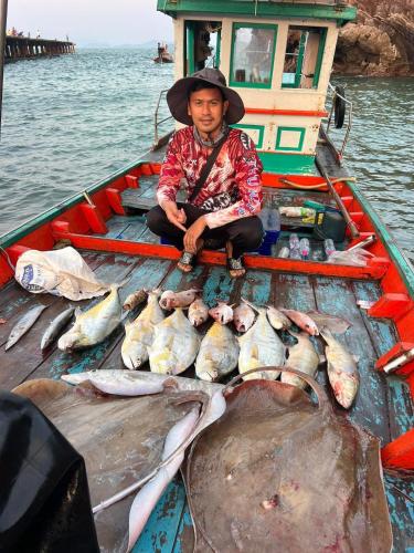 a man sitting on a boat with a bunch of fish at Manee Poolvilla in Khanom
