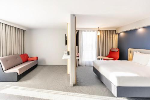 a hotel room with a bed and a couch at Holiday Inn Express Paris - Poissy by IHG in Poissy