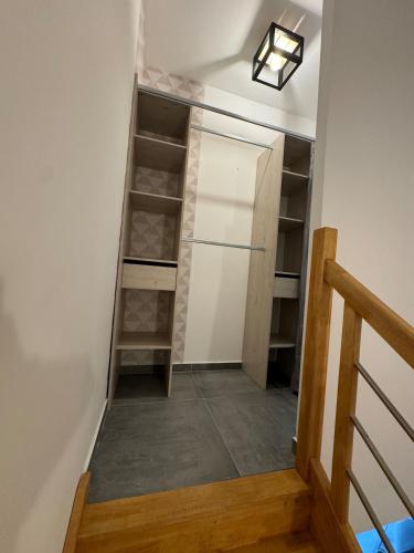 un couloir avec un placard avec des étagères et un escalier dans l'établissement T2 duplex en RDC, à Bastelicaccia