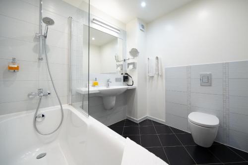 a bathroom with a tub and a sink and a toilet at Bellevue Park Hotel Riga with FREE Parking in Rīga