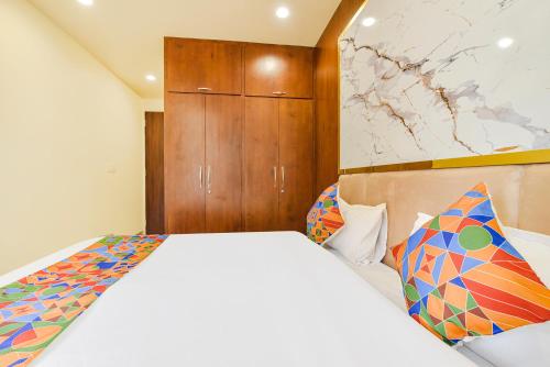 a bedroom with a white bed and a wooden cabinet at FabHotel Blooming Beds Pearl in Jaipur