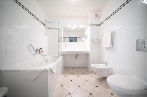 a white bathroom with a toilet and a sink at Bellevue Park Hotel Riga with FREE Parking in Rīga