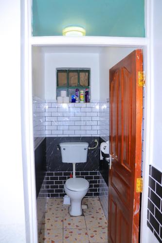 a bathroom with a white toilet and black tiles at Syn Homes in Nairobi