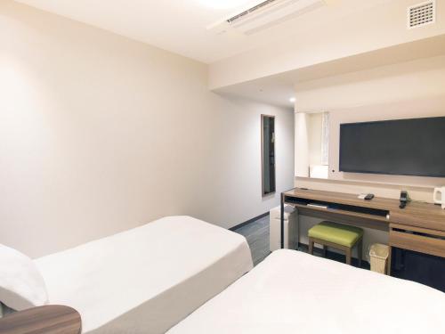 a room with two beds and a desk with a television at Hearton Hotel Shinsaibashi Nagahoridouri in Osaka