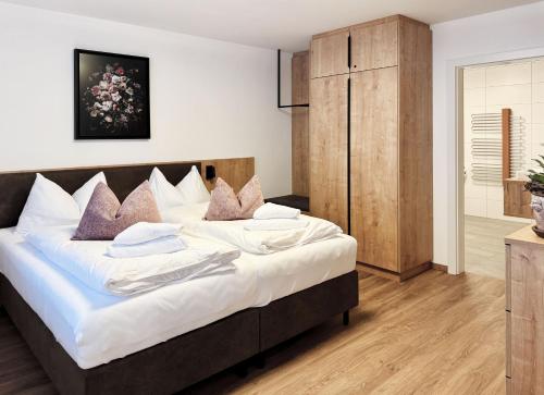 a bedroom with a large bed with white sheets and pillows at Alpenstolz Damüls Haus 4 - Stilvoll urlauben in den Bergen in Damuls