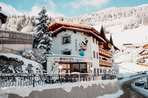 a snow covered building with a sign on it at Kinderhotel Laderhof in Ladis
