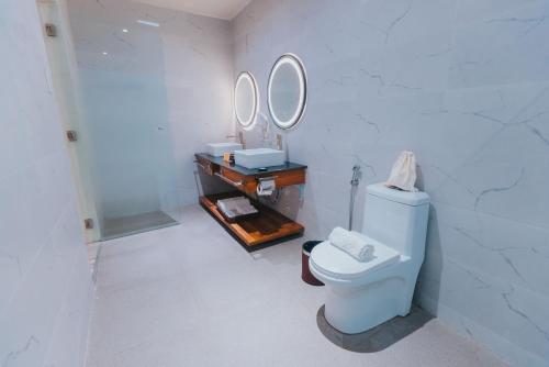 a bathroom with a toilet and two mirrors on the wall at SureStay Studio by Best Western Clarkview Angeles City in Angeles