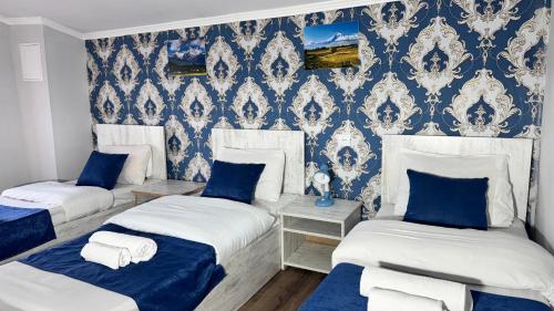three beds in a room with blue and white wallpaper at Byurakan Guesthouse & Cottage in Byurakan