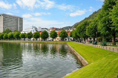 a park with a lake in front of a city at BREEZE Hotel Victoria - Self-Service in Bergen