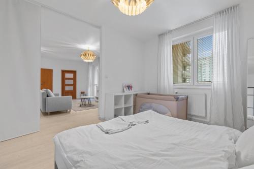 a white bedroom with a bed and a chair at AH Bosakova Elegant in Bratislava