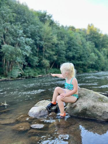 a little girl sitting on a rock in a river at Camp Kyllburg in Kyllburg
