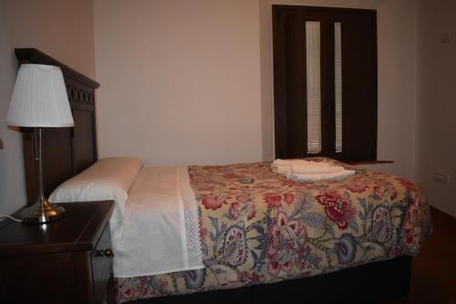 a bedroom with a bed with a lamp and a window at Apartamentos Bodeguetas in Constantina
