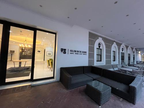 a living room with a black couch and a table at Near CTICC Professional & Cosy Hotel Room in Cape Town