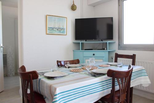 une salle à manger avec une table avec des chaises et une télévision dans l'établissement Appartement 2 pièces - LA ROCHELLE - LR240-602, à La Rochelle