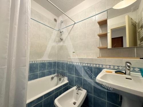 La salle de bains bleue et blanche est pourvue d'un lavabo et d'une baignoire. dans l'établissement T2 1ERE LIGNE MER, PKG, WI-FI, DIRECT PLAGES, à Sète