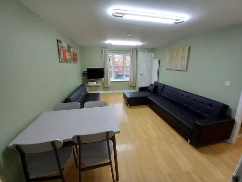 a living room with a black couch and a table at Perfect for construction workers and building contractors in Manchester