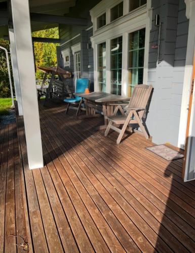 a wooden deck with a table and chairs on a house at Villa Iltaranta - Cottage on the shore of Lake Saimaaa in Savonlinna