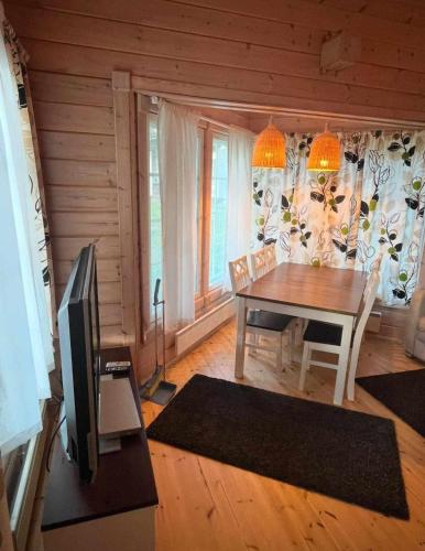 a dining room with a table and a television at Villa Iltaranta - Cottage on the shore of Lake Saimaaa in Savonlinna
