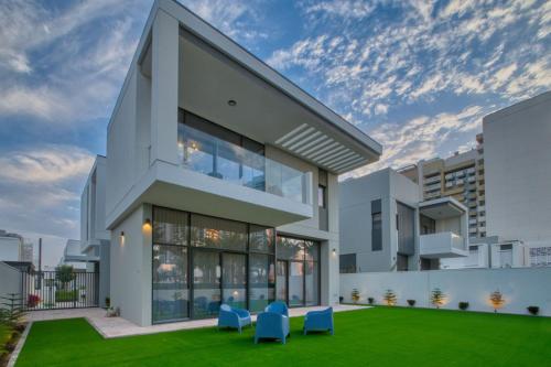 a large white building with blue chairs in a yard at Dubai Luxury 4BR Villa in Murooj Al Furjan in Dubai