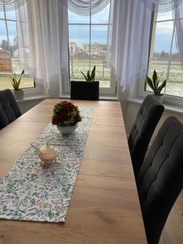a dining room with a long table with chairs and windows at Dworek pod Krzyżtoporem Ujazd Agroturystyka- pokoje do wynajęcia in Iwaniska