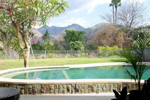 a swimming pool in a yard with mountains in the background at Kalkun Villa Amed in Amed