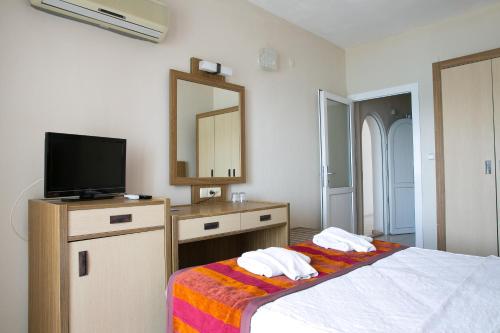 a bedroom with a bed with a tv and a mirror at Greenport Bodrum Hotel in Guvercinlik