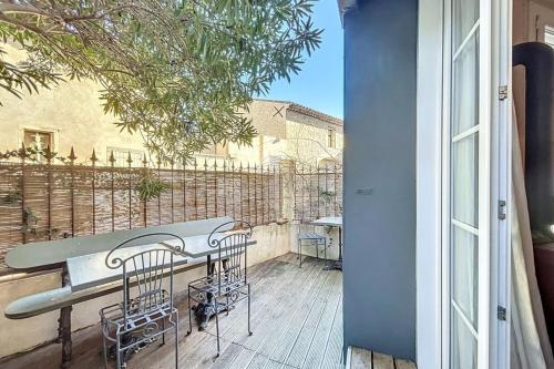 a balcony with a table and chairs on a deck at La Bade - Maison d'artiste proche des pontons in Peyriac-de-Mer