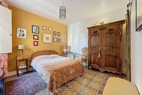 a bedroom with a bed and a wooden cabinet at La Bade - Maison d'artiste proche des pontons in Peyriac-de-Mer