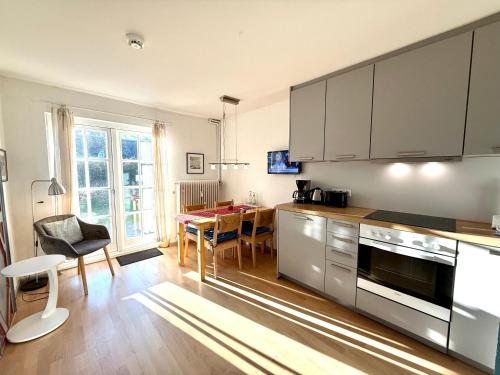 a kitchen with stainless steel appliances and a dining table at Gartenwohnung in Nieblum