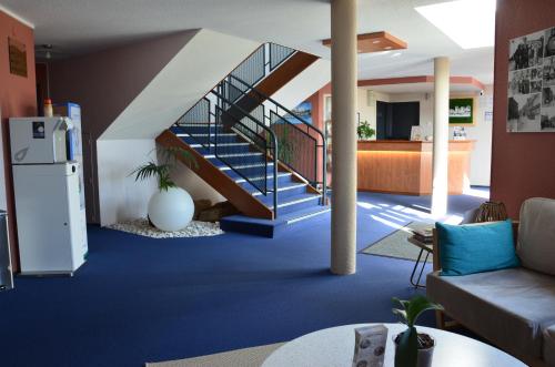 a living room with a staircase with blue carpet at BRIT HOTEL Caen Hérouville in Hérouville-Saint-Clair