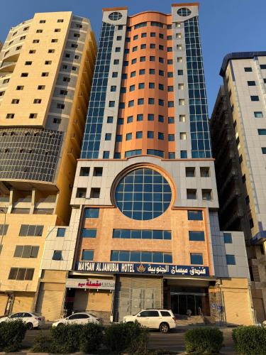 Un edificio alto con coches aparcados delante. en Maysan Al Janubia Hotel, en Al ‘Azīzīyah
