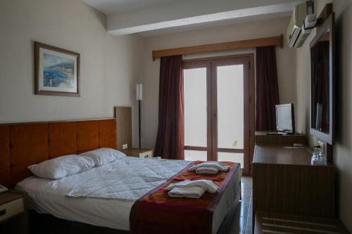 a hotel room with a bed and a window at Greenport Bodrum Hotel in Guvercinlik