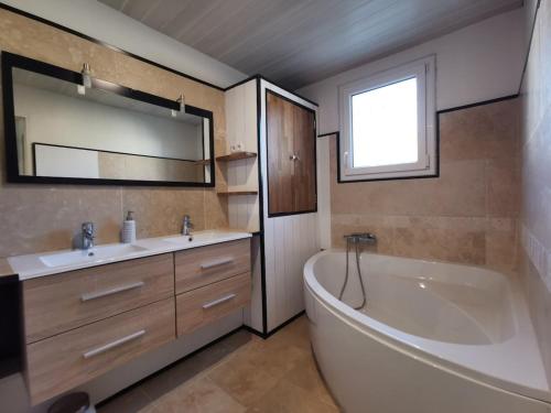 une salle de bain avec une baignoire, un lavabo et un miroir dans l'établissement Air-conditioned house garden parking pool, à Rognonas