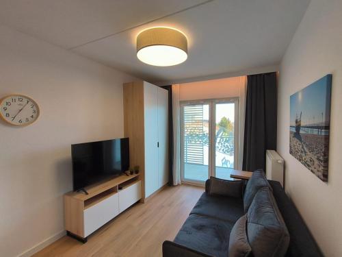 a living room with a couch and a tv and a clock at ReVital Mechelinki by Homeprime Parking Free in Mechelinki