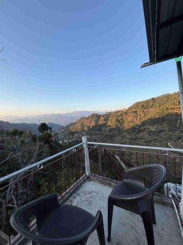 two chairs sitting on a balcony with a view at Odyssey Stays Khirsu in Pauri