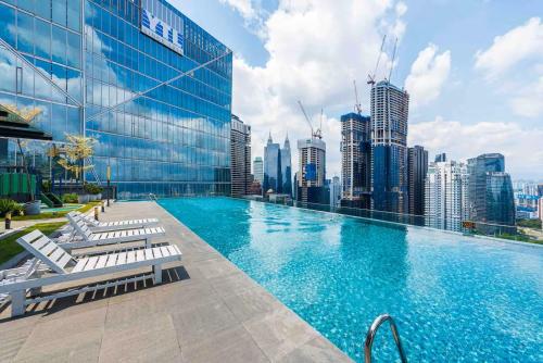 a swimming pool with chairs and a city skyline at Dorsett Residences Bukit Bintang in Kuala Lumpur