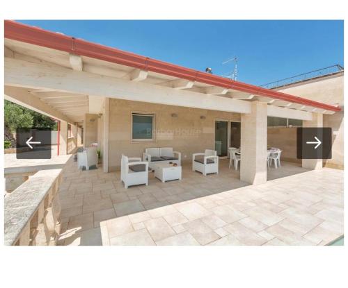 a patio with white chairs and tables and a roof at Villa Ilaria in Capitolo