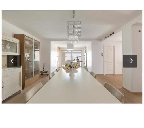 a dining room with a white table and a kitchen at Villa Ilaria in Capitolo